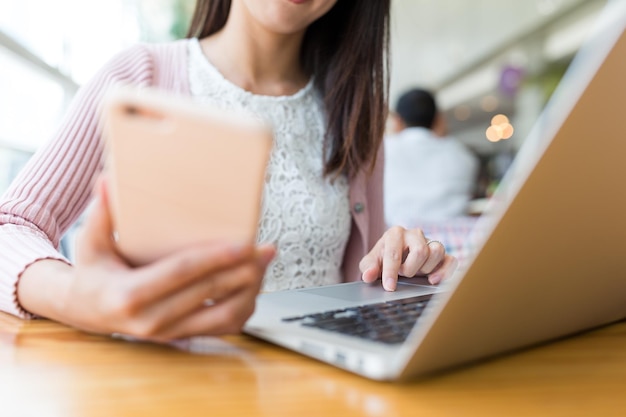 Vrouw met behulp van laptopcomputer en mobiele telefoon