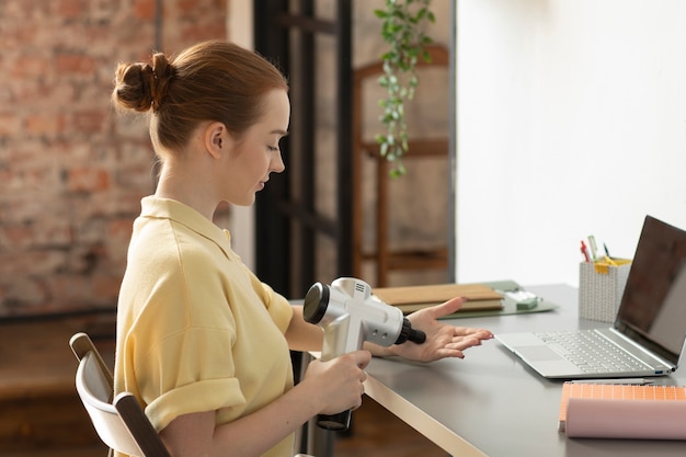 Foto vrouw met behulp van massage pistool op palm medium shot