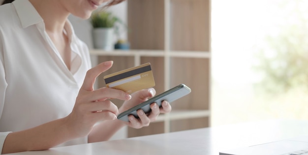 Vrouw met behulp van mobiele slimme telefoon online bankieren met creditcard geldoverdracht succesvol invullen van factuurgegevens in laptop aankoopproducten op e-commerce winkel betaling winkelen transactie