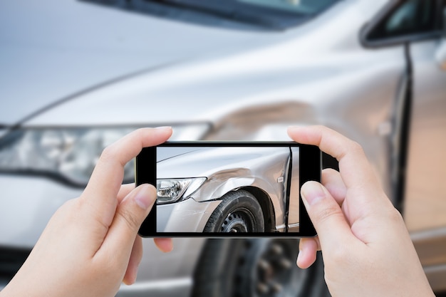 Vrouw met behulp van mobiele smartphone foto auto-ongeluk ongeval van de schade aan de auto voor ongevallenverzekering