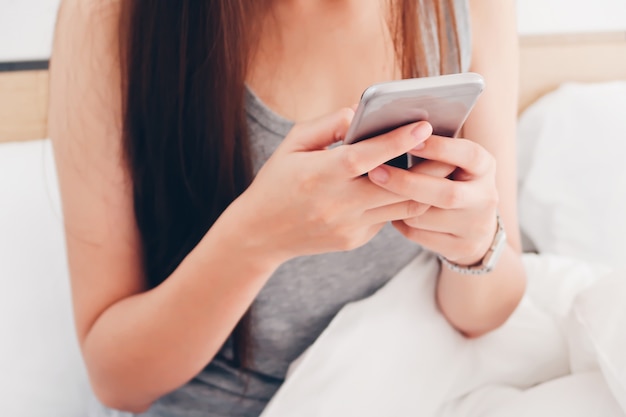 Foto vrouw met behulp van slimme telefoon op bed.