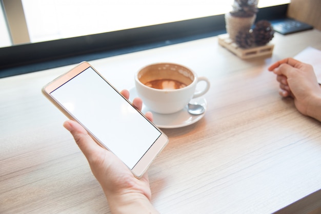 Vrouw met behulp van smartphone, close-up, koffie en planning boek op de achtergrond