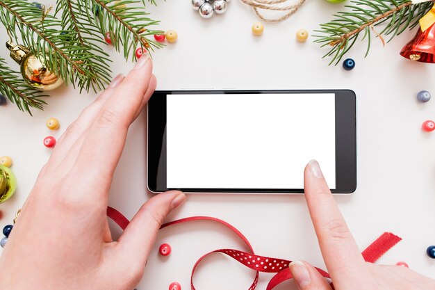 Vrouw met behulp van smartphone met leeg scherm op tafel met kerstversiering