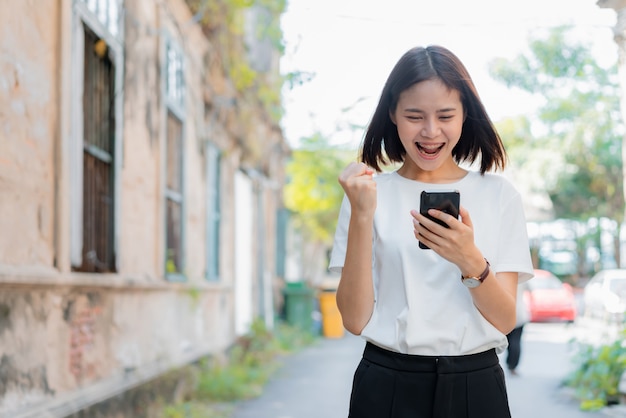 Vrouw met behulp van smartphone voor de toepassing en het tonen van een gelukkig gebaar.