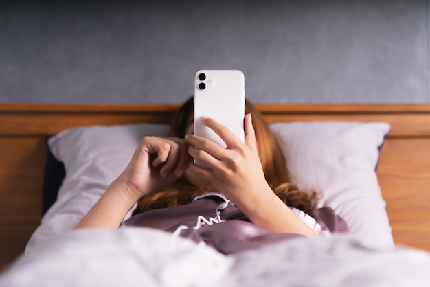 Vrouw met behulp van telefoon op bed na wakker