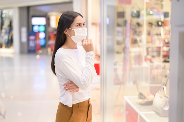 Vrouw met beschermend masker winkelen onder Covid-19 pandemie in winkelcentrum