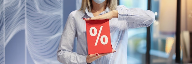 Vrouw met beschermend medisch masker met rood bord met kortingspercentages in de winkel zwart