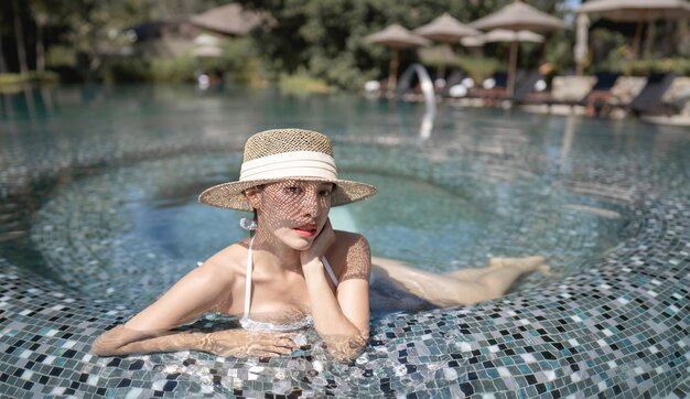 Vrouw met bikini en strohoed ontspannen in het zwembad. spa-behandelingen concept.