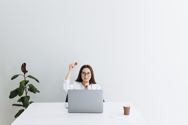 Vrouw met bitcoin zittend aan de tafel op grijze achtergrond