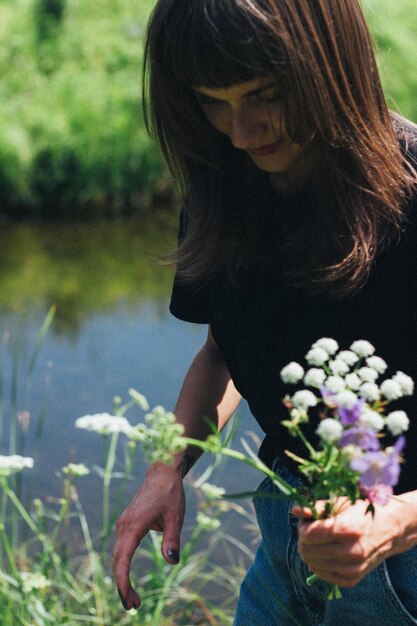 Foto vrouw met bloemen bij het meer