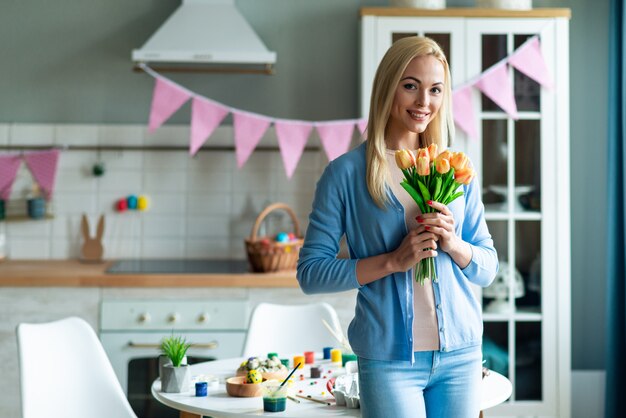 Vrouw met bloemen in ingerichte keuken.