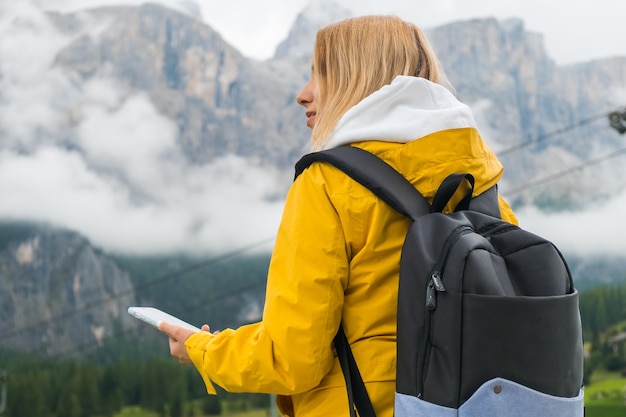 Vrouw met blond haar controleert de route met behulp van een smartphone in de Dolomieten Alpen