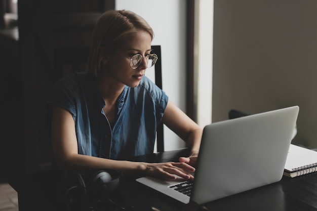 Vrouw met blond haar die thuis via een laptop werkt of leert