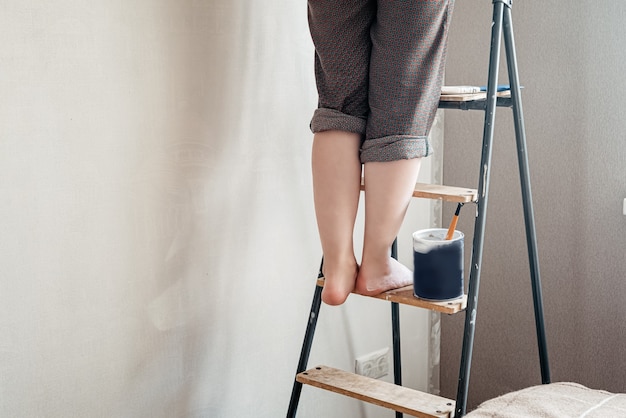 Vrouw met blote voeten gekleurd met witte verf staat op trapladder