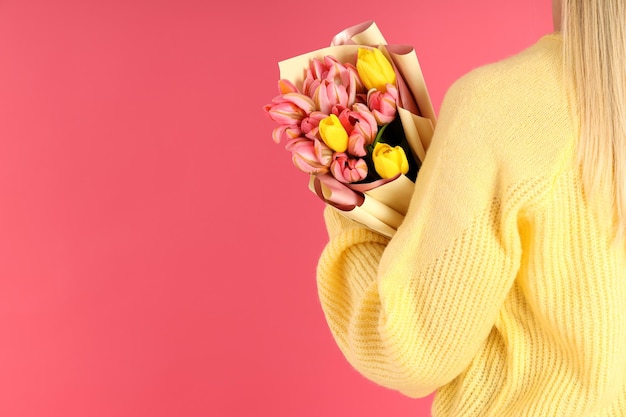 Vrouw met boeket bloemen op roze achtergrond