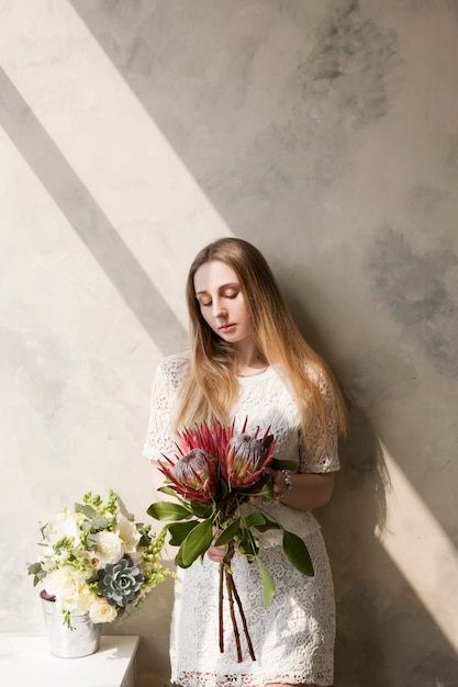 Vrouw met boeket van grote zeldzame bloemen op muur achtergrond. Mooi meisjescadeau, levering van boeketten, floristisch winkelconcept