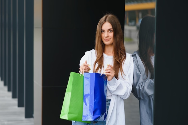Vrouw met boodschappentassen van luxe merken wandelen in de buurt van winkelcentrum