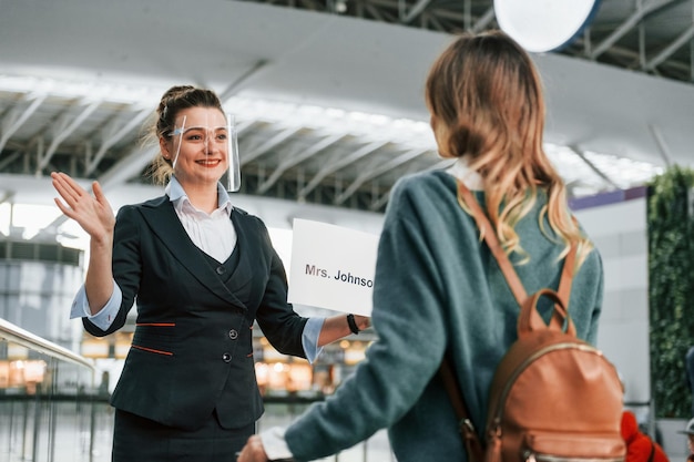 Vrouw met bord met tekst Jonge vrouwelijke toerist is overdag op de luchthaven