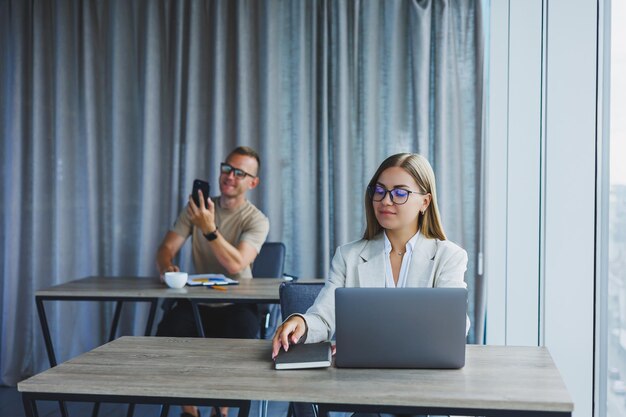 Vrouw met bril aan tafel tijdens het werken met collega's op kantoor Concept van moderne succesvolle zakenmensen Man en vrouw zitten aan houten tafels