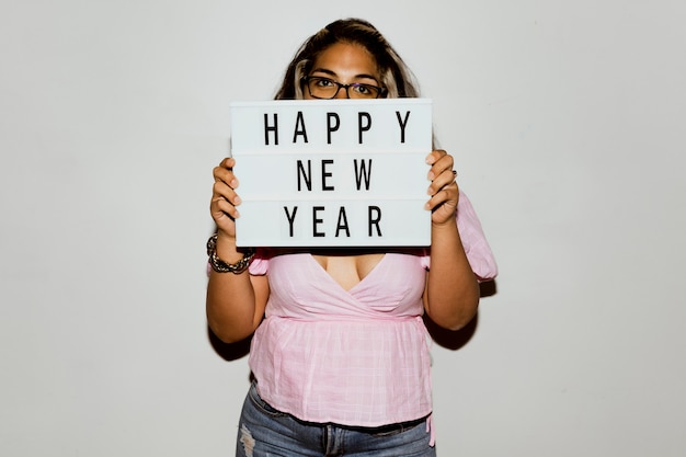 Vrouw met bril die een gelukkig nieuwjaarsbord opheft