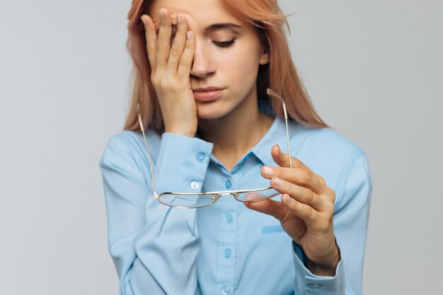 Vrouw met bril houden haar ogen wrijven, voelt zich moe na het werken op de laptop.