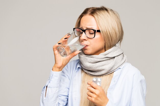 Vrouw met bril, overhemd, verpakte sjaal met glas water en pillen