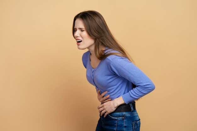 Vrouw met buikpijn geïsoleerd op beige achtergrond Menstruele krampen periode pijn concept