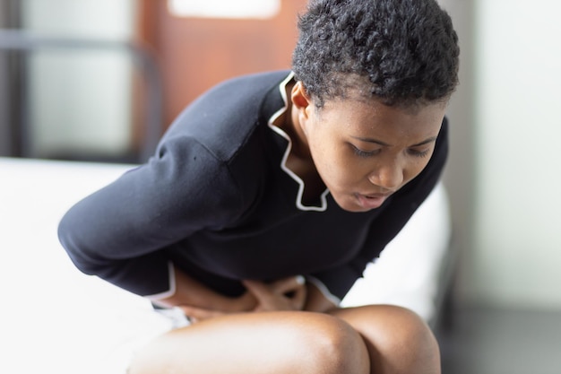 Vrouw met buikpijn zieke zwarte Afrikaanse vrouw die lijdt aan buikpijn menstruatie kramp buikpijn voedselvergiftiging gastritis zure reflux