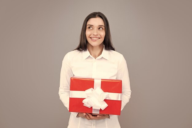 Vrouw met cadeau Portret van opgewonden jong meisje met geschenkdoos geïsoleerd grijze achtergrond Mooi meisje met cadeau