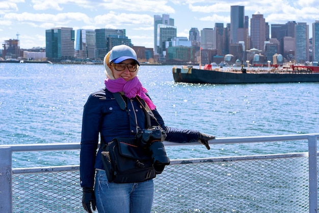 Foto vrouw met camera aan boord aan de waterkant van de prachtige stad in boston, ma, verenigde staten.