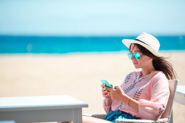Vrouw met cellphone in openlucht op het strand. Toerist met behulp van mobiele smartphone.