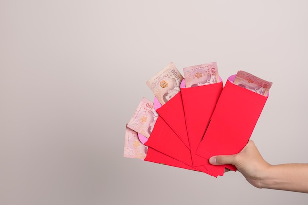 Vrouw met Chinese rode envelop met Thaise baht-geldgift voor gelukkige nieuwe maanjaarvakantie