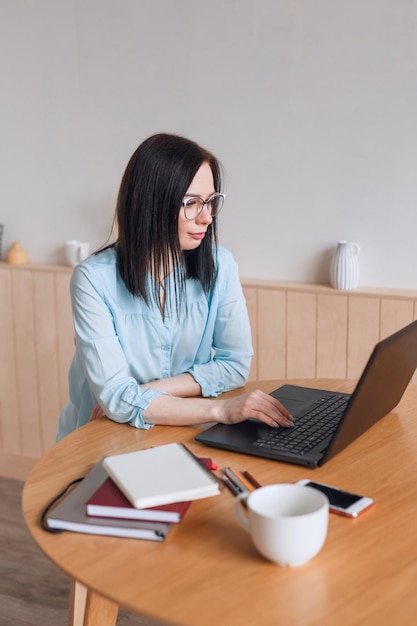 Foto vrouw met computer en smartphone die binnenshuis in een thuiskantoor werkt