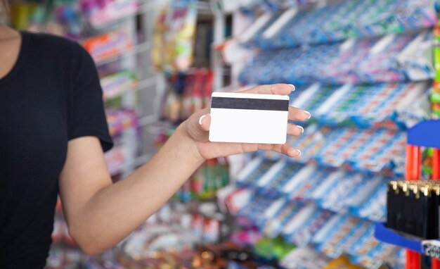 Vrouw met creditcard bij supermarkt.