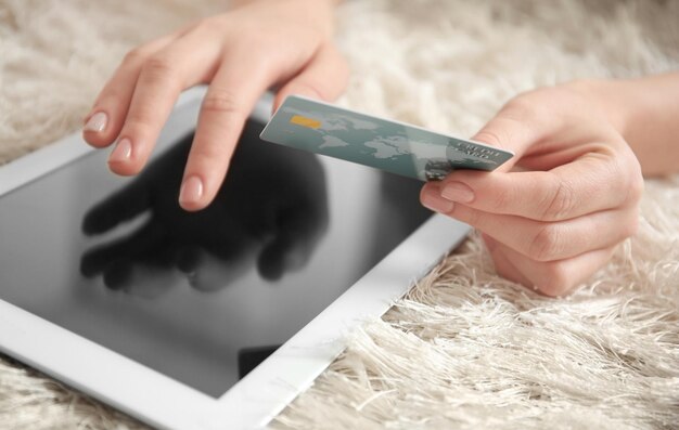 Vrouw met creditcard tijdens het gebruik van tabletcomputer thuis close-up Internet shopping concept