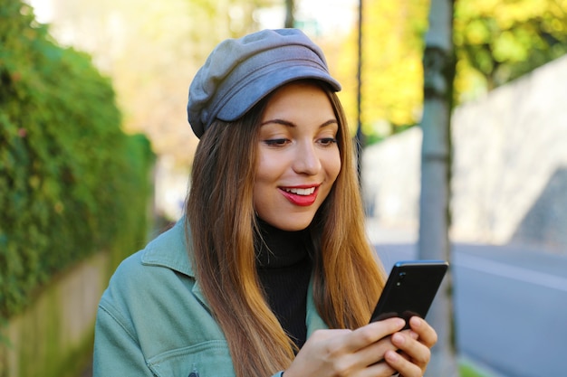 Vrouw met de hals van het hoedenpolo en jasje messaging met mobiele telefoon