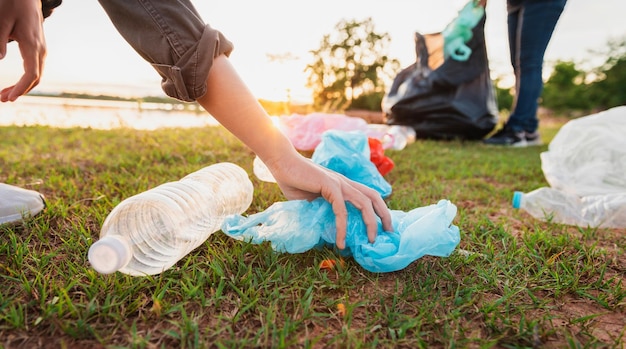 Vrouw met de hand oppakken van vuilnis plastic fles voor het schoonmaken in het park