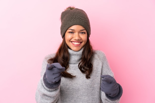 Vrouw met de winterhoed over geïsoleerde roze muur