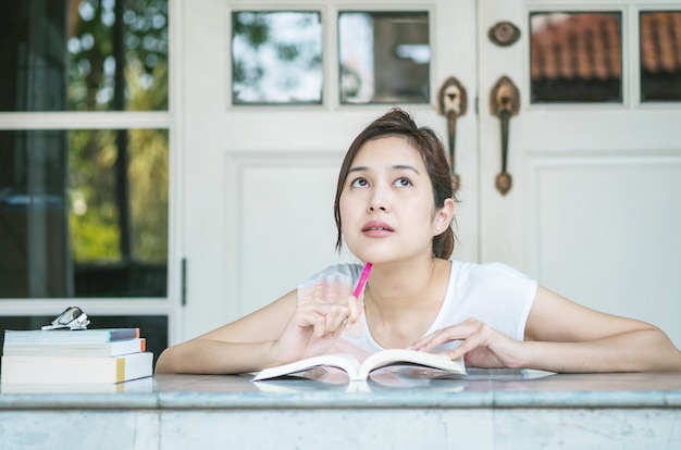 Vrouw met denken gezicht met een boek over marmeren tafel