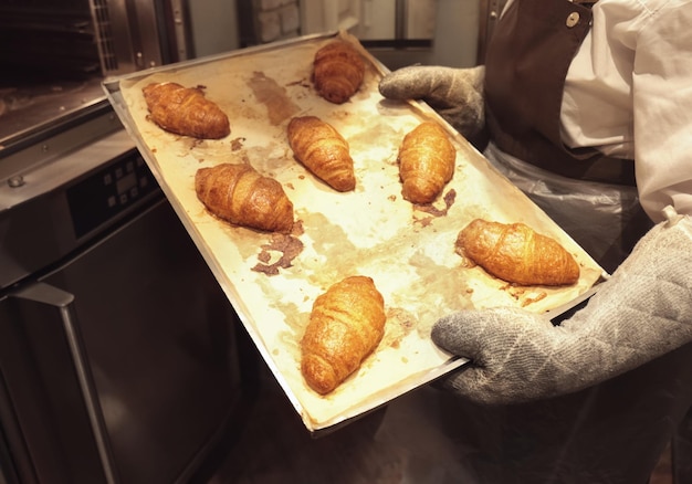 Foto vrouw met dienblad met croissants in de bakkerij