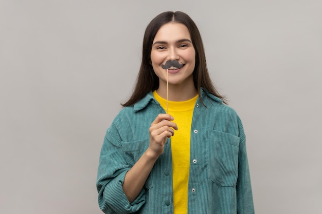 Vrouw met donker haar staande met papieren snor op stok feestelijke stemmingsmaskerade