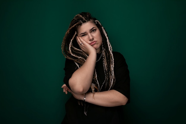 Vrouw met dreadlocks die voor een groene achtergrond staat