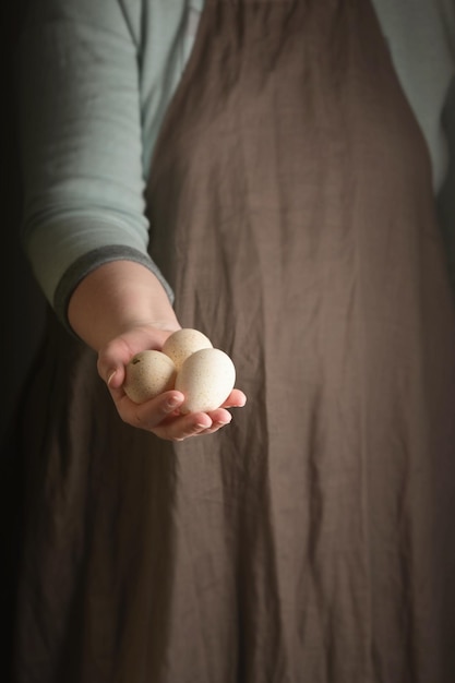 Vrouw met drie kalkoeneieren in de hand Rustieke stijl Vertical