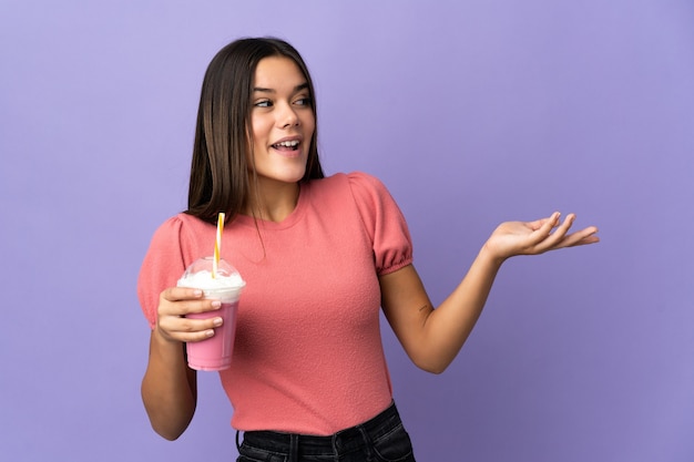 vrouw met een aardbeienmilkshake met verrassingsuitdrukking terwijl ze naar de zijkant kijkt