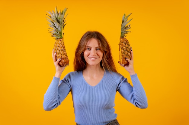 Vrouw met een ananas in zonnebril portret met ananas gesneden in halve studio op gele achtergrond