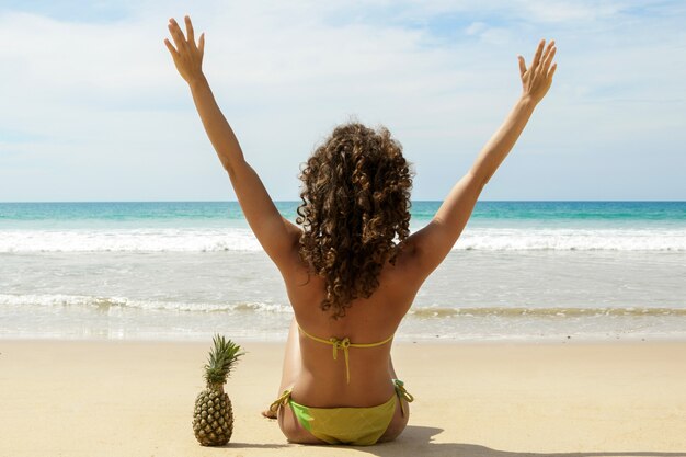 Vrouw met een ananasfruit op het strand
