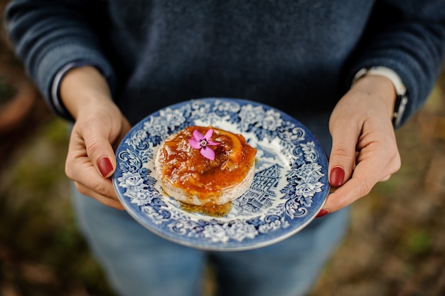 Vrouw met een blauw versierd bord met een heerlijke sinaasappeljam op het brood