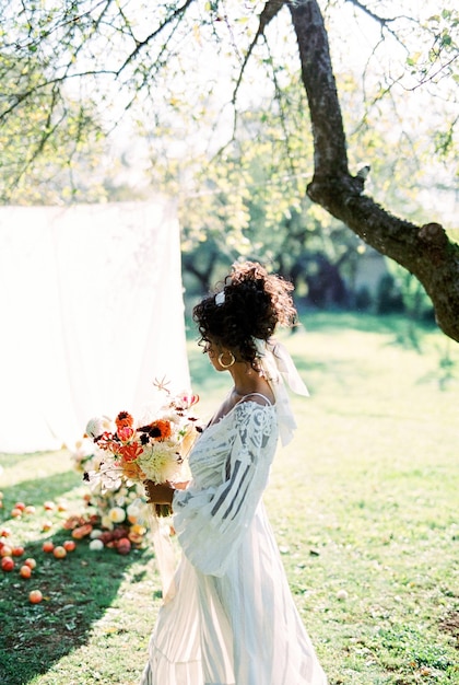 Vrouw met een boeket bloemen in de tuin tegen de achtergrond van witte gordijnen. Hoge kwaliteit foto