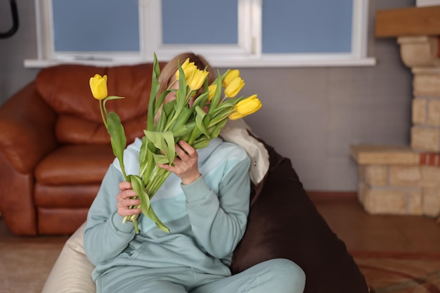 Vrouw met een boeket gele tulpen in de kamer