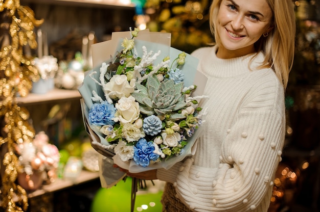 Vrouw met een boeket witte rozen, anjer, kunstmatige takken en sappig